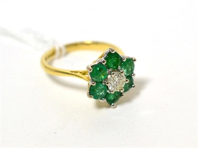 Lot 47 - An 18 carat gold diamond and emerald cluster ring, a round brilliant cut diamond within a...