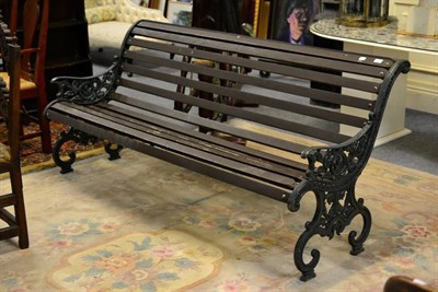 Lot 1157 - A slatted wooden garden bench with painted cast iron ends