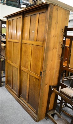 Lot 1208 - A 20th century panelled oak wardrobe with twin sliding doors