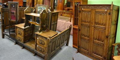 Lot 1256 - A 1930's linen fold carved oak bedroom suite; comprising wardrobe, dressing table, bedside cabinet