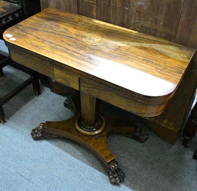 Lot 1294 - A 19th century rosewood fold over card table raised on a waisted x-form platform base and paw feet