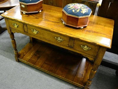 Lot 1297 - A reproduction oak dresser/side table, fitted with three drawers, on turned supports and with...