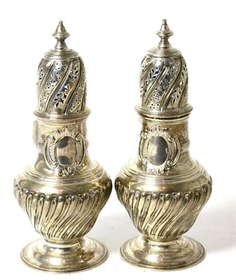 Lot 174 - A pair of Victorian silver sugar casters by CSH, London, 1884 of Wrythen form with blank cartouches