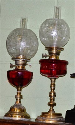 Lot 474 - Two Victorian cranberry and brass oil lamps, with etched glass shades