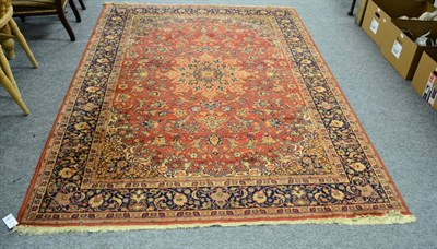 Lot 1143 - A machine made rug of Persian design, the terracotta field of vines around a medallion framed...