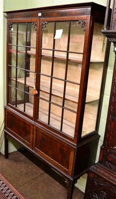 Lot 1212 - A glazed display cabinet with cupboard below, raised on square supports