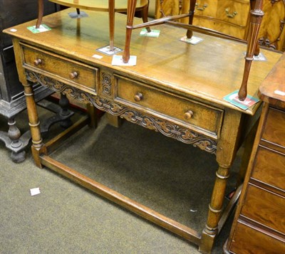 Lot 1299 - An early 20th century carved oak hall table with two drawers raised on gun barrel legs