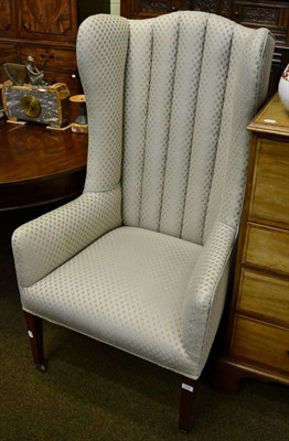 Lot 1342 - An upholstered high back wing armchair on tapering square support