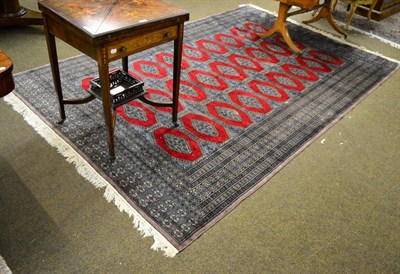 Lot 1359 - A Lahore 'Bukhara' carpet, Pakistan, the blood red field with three columns of guls enclosed by...