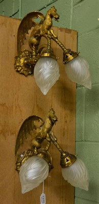 Lot 1370 - A pair of gilt metal dragon form wall lights with glass shades