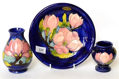 Lot 226 - Walter Moorcroft Magnolia pattern plate and two vases on blue grounds (3)