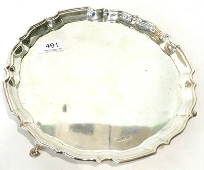 Lot 491 - A circular silver salver, Sheffield 1925, plain, with shaped rim on three hoof supports, 26.5cm...