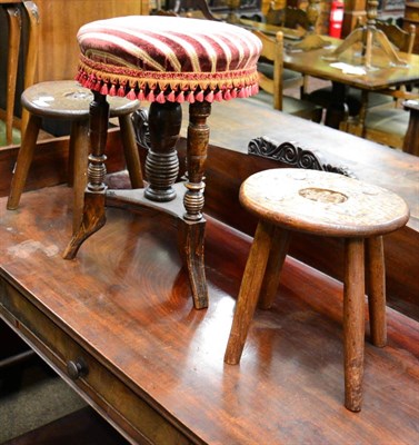 Lot 1263 - Two carved oak milking stools in Arts & Crafts taste, together with an adjustable piano stool