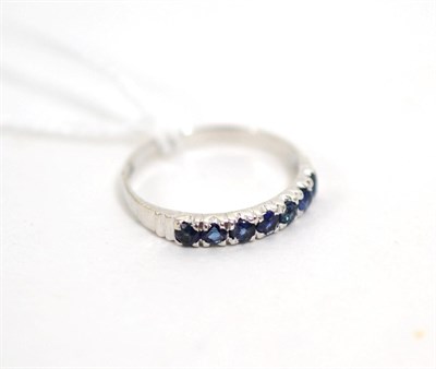 Lot 38 - A sapphire half hoop ring, finger size M1/2, stamped '14K'