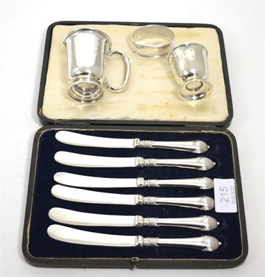 Lot 215 - A cased set of six silver handled tea knives, silver christening mug, silver egg cup and '830'...