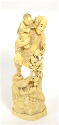 Lot 275 - A Meiji period ivory okimono of a man carrying a young boy, on integral naturalistic base