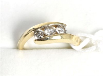 Lot 93 - A diamond three stone ring, graduated round brilliant cut diamonds tension set between yellow twist