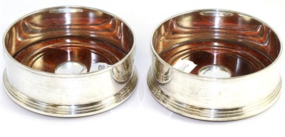 Lot 145 - A pair of modern silver bottle coasters each with turned wooden bases