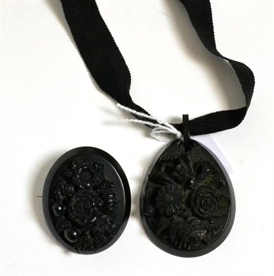 Lot 188 - A carved jet pendant, of oval form and carved in high relief with a floral spray, on a black fabric