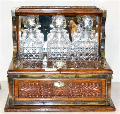 Lot 372 - A late Victorian/Edwardian carved oak combination tantalus with game drawer, with three square...