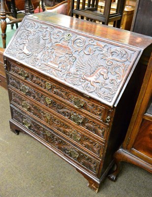 Lot 1254 - An oak bureau the fall front and drawers with an elaborate carving