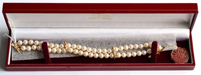 Lot 159 - A double strand cultured pearl bracelet with 18 carat gold diamond set bow links, length 19cm