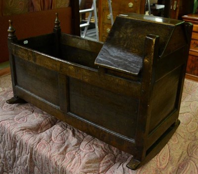 Lot 1344 - An 18th century joined oak cradle, with canopy hood above panelled sides, raised on sledge...