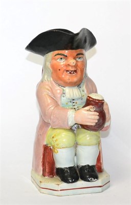 Lot 141 - A pearlware Toby Jug, early 19th century, of traditional form holding a jug and pipe