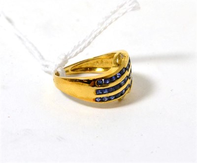 Lot 484 - A sapphire and diamond ring, three rows of step cut sapphires in yellow channel settings...