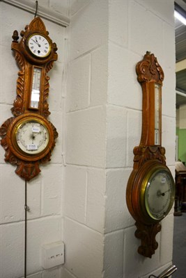 Lot 1155 - A carved oak aneroid barometer combined with a thermometer box and timepiece, and another...