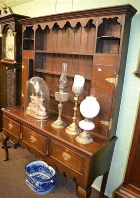 Lot 1270 - A late George III oak dresser, early 19th century, with a bold cornice above fixed shelves and...