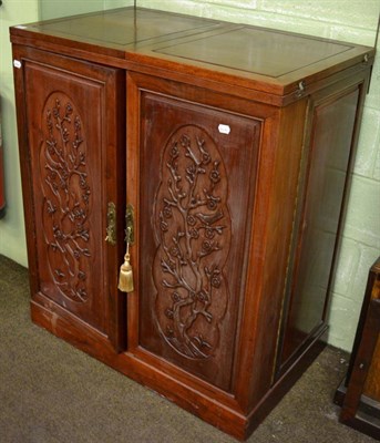 Lot 1280 - A Chinese cabinet, the fold over top above carved panel doors opening to reveal an arrangment...