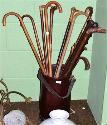 Lot 138 - A leather stick stand containing a selection of wood sticks and canes