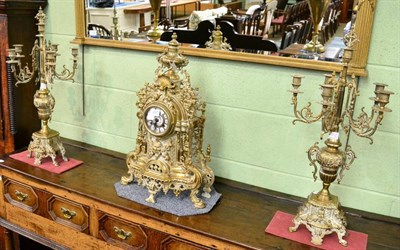 Lot 357 - A reproduction gilt metal striking mantel clock with six light candelabra garniture