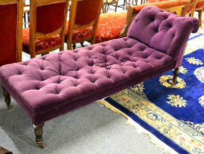 Lot 1061 - A purple upholstered buttoned chaise longue, on turned supports and castors