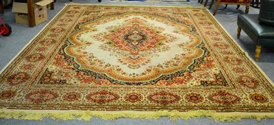 Lot 1063 - A machine made carpet, the cream field with floral medallion framed with cartouche borders 392cm by