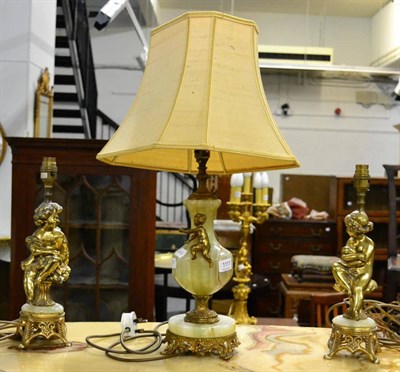 Lot 1111 - Three gilt metal and onyx table lamps decorated with putti