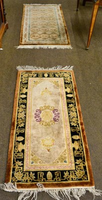 Lot 1210 - A Chinese rug, the field with columns of roundels, enclosed by ivory borders, together with another