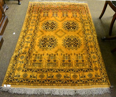 Lot 1221 - An Afghan gold rug, the field with four large flower heads enclosed by stylised vine borders, 187cm