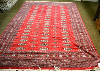 Lot 1291 - A Lahore Bokhara carpet, the blood red field with three columns of guls, enclosed by sunburst motif