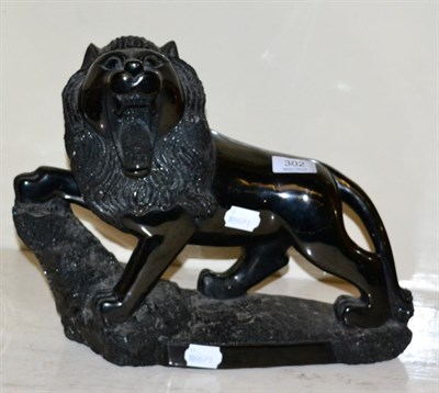 Lot 302 - A coal carving of a lion, 20th, modelled standing on integral base, 38cm in length