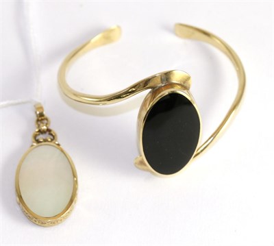 Lot 361 - A 9ct gold onyx set bangle and a 9ct gold onyx and mother-of-pearl pendant (2)