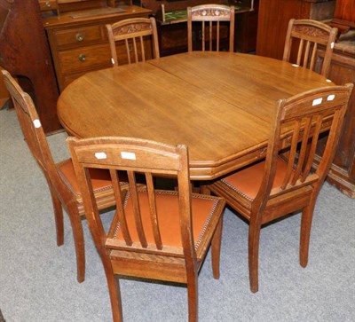 Lot 1174 - An oak extending table with six matching chairs upholstered in close nailed leather