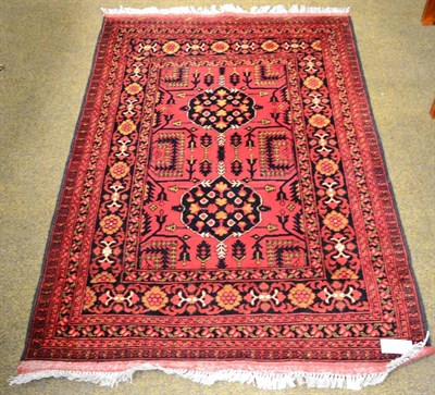 Lot 1283 - An Afghan rug, the crimson field with two medallions enclosed by floral borders 144cm x 103cm