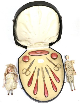 Lot 243 - A cased coral pink enamel manicure set, a bisque head doll and another doll