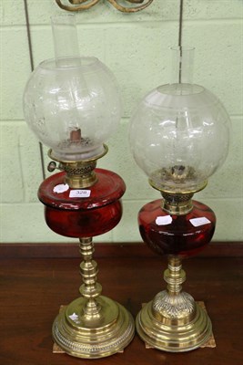 Lot 328 - Two Victorian cranberry and brass oil lamps, with etched glass shades