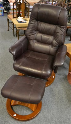 Lot 1120 - A GFA brown leather reclining arm chair with matching footstool