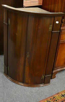 Lot 1167 - A Georgian oak bow fronted corner cupboard