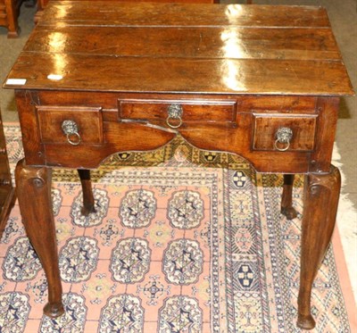 Lot 1309 - An 18th century oak lowboy with three frieze drawers raised on stout cabriole legs (feet...