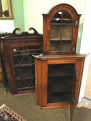 Lot 1380 - A George III panelled oak hanging corner cupboard together with a smaller glazed example with...